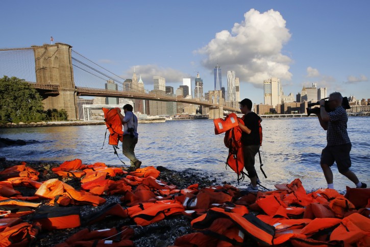Advocates with Oxfam America place life jackets on the ground along the New York City waterfront, to draw attention to the refugee crisis, Friday, Sept. 16, 2016, in the Brooklyn borough of New York. Many of the life jackets used for the Friday action were used by adult and child refugees and collected on beaches in Greece. The undertaking was a prelude to next week's United Nations Summit for Refugees and Migrants. (AP Photo/Mark Lennihan)