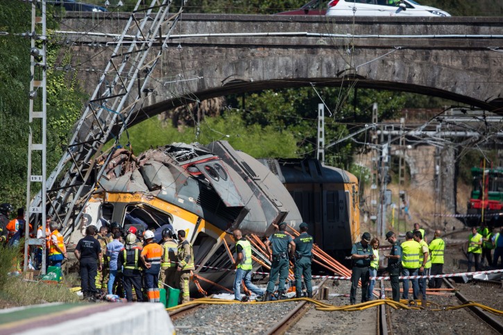 Emergency personnel attend the scene after a passenger train traveling from Vigo to Porto, in neighboring Portugal, derailed in O Porrino, in  Spain's northwestern Galicia region, killing  and injuring people, authorities said Friday Sept. 9, 2016 . The train had three cars. The front one came completely off the track and hit a post next to the line, leaving it leaning to one side. The back two cars were partly off the tracks. Spanish media said the train was carrying around 60 passengers.(AP Photo/Lalo R. Villar)