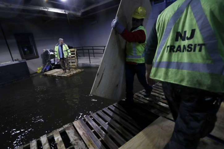 New Jersey Transit workers lay down pallets and boards for commuters to walk on a flooded hallway adjacent to the site of a train crash at the Hoboken Terminal, Friday, Sept. 30, 2016, in Hoboken, N.J. Commuters are using alternative travel in and out of Hoboken a day after a commuter train crashed into the rail station, killing one person and injuring more than 100 people. (AP Photo/Julio Cortez)