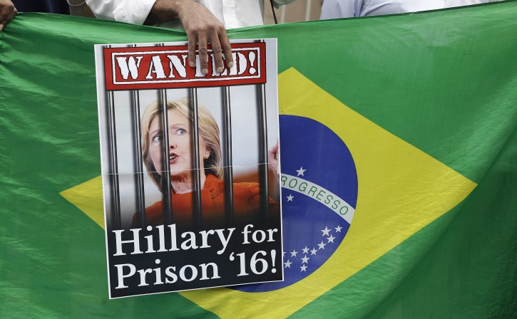 A demonstrator holds a poster of U.S. presidential candidate Hillary Clinton, depicted behind bars in a "wanted" sign, during a rally in support of her rival Donald Trump in Sao Paulo, Brazil, Saturday, Oct. 29, 2016. A right-wing group organized the small rally via social media. (AP Photo/Andre Penner)