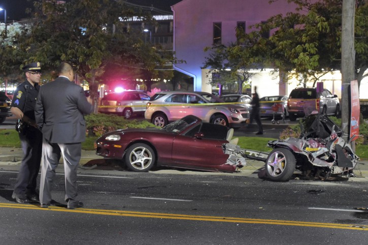 Police survey the wreckage of a Mazda Miata that was split in half after it was struck by a Mercedes-Benz in Rockville Centre, on New York's Long Island, Friday Oct. 14, 2016. Miraculously nobody suffered life-threatening injuries. The driver of the Mercedes-Benz and his 25-year-old female passenger had to be extricated from their vehicle. (Paul Mazza/Newsday via AP)