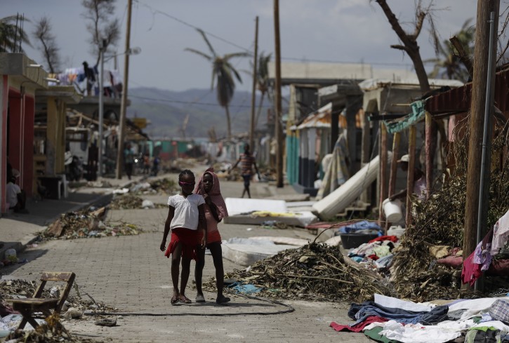 Girls make their way down a street littered with debris left by Hurricane Matthew in Les Anglais, Haiti, Monday, Oct. 10, 2016. Nearly a week after the storm smashed into southwestern Haiti, some communities along the southern coast have yet to receive any assistance, leaving residents who have lost their homes and virtually all of their belongings struggling to find shelter and potable water. (AP Photo/Rebecca Blackwell)