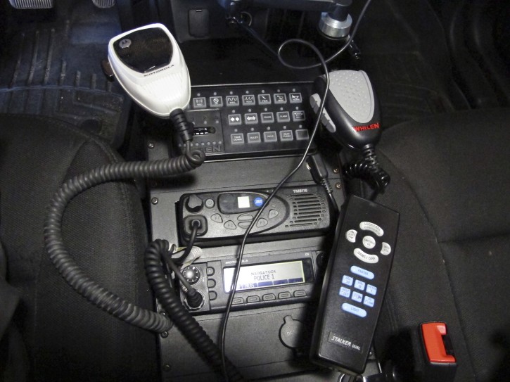 In this Thursday, Oct. 6, 2016 photo, a radio in a police cruiser sits between the front seats in Naugatuck, Conn. While many police departments around the country are concealing their dispatch communications through encryption, Naugatuck, among others, has decided to keep theirs open to the public. Some police chiefs have said their officers may not be able to communicate on encrypted systems with first-responders in neighboring towns. (AP Photo/Dave Collins)