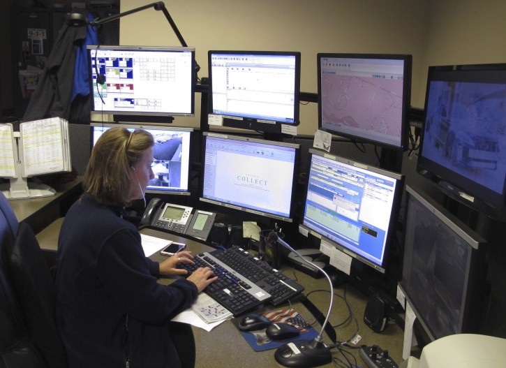 In this Thursday, Oct. 6, 2016 photo, dispatcher Kelly Orsini works at her communications desk at the police department in Naugatuck, Conn. While many police departments around the country are concealing their dispatch communications through encryption, Naugatuck, among others, has decided to keep theirs open to the public. Some police chiefs have said their officers may not be able to communicate on encrypted systems with first-responders in neighboring towns. (AP Photo/Dave Collins)