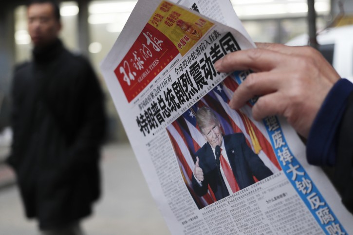 A man reads a Global Times newspaper front cover with a headline "U.S. President-elect Donald Trump deliver a mighty shock to America" at a news stand in Beijing, Thursday, Nov. 10, 2016. Donald Trump's promise to put America first helped propel him to the U.S. presidency. But he also unleashed uncertainty on the global economy by skewering trading partners and offering few specifics that might calm allies or businesses. (AP Photo/Andy Wong)