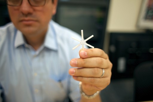 The star-shaped drug delivery device, held here by Giovanni Traverso, a Koch Institute research affiliate, can be folded inward and encased in a smooth capsule. Once ingested, the device delivers a full drug payload gradually over weeks or even months.  Photo: Melanie Gonick
