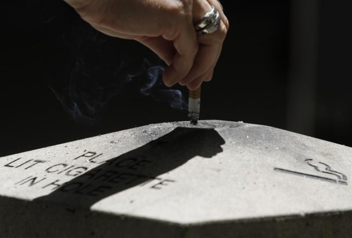 FILE - A woman disposes a cigarette in Los Angeles, California, May 31, 2012.  Reuters
