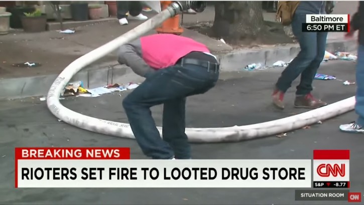 Gregory Butler is seen on live CNN broadcasting bending down punching a hole into the fire hose