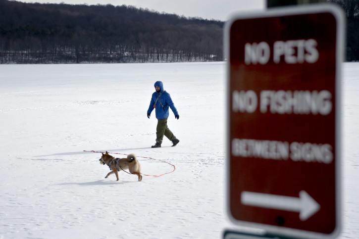 Jay Churkin and his dog Siba play on the frozen Lake Arthur in Moraine State Park while temperatures were in the single digits, Saturday, Jan. 6, 2018, in Portersville, Pa. Pennsylvanians continue to deal with bone-chilling temperatures and related weather issues that have gripped the state in recent weeks. (AP Photo/Keith Srakocic)