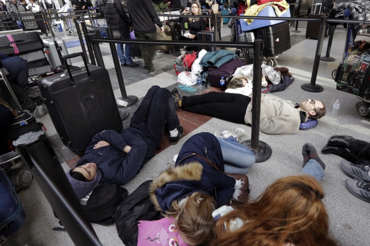 Avianca passengers lay on the floor of New York's John F. Kennedy Airport Terminal 4, Monday, Jan. 8, 2018. The Port Authority of New York and New Jersey said Monday it will investigate the water pipe break that added to the weather-related delays at Kennedy Airport and will "hold all responsible parties accountable." (AP Photo/Richard Drew)