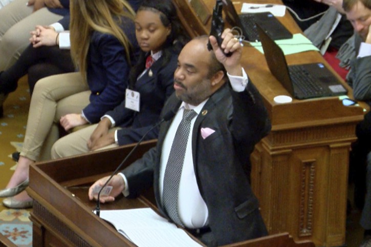 In this video frame, Rep. Charles Young, D-Meridian, holds up an unloaded semi-automatic pistol during a debate in the House chamber at the Capitol on Thursday, Feb. 8, 2018, in Jackson, Miss. Young says he was trying to make a point about the hypocrisy of laws and rules about where people may carry guns. (Courtney Ann Hall/WLBT-TV, via AP)