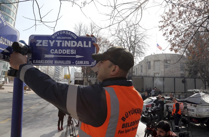An Ankara municipality worker fixes the new street sign, "Olive Branch Street" in Turkish, named after Turkey's military operation to drive out the Syrian Kurdish militia of an enclave in northwest Syria, in Ankara, Turkey, Monday, Feb. 19, 2018. Municipality workers on Monday took down the street sign for Nevzat Tandogan Street where the U.S. Embassy is located and replaced it with one that reads "Olive Branch Street." (AP Photo/Burhan Ozbilici)