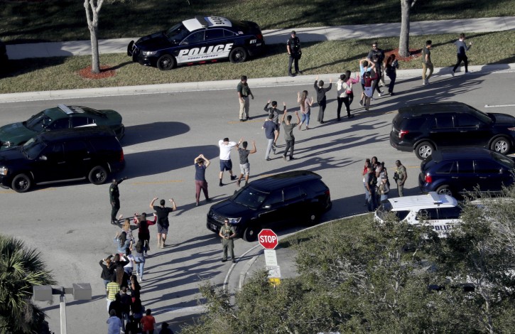FILE - In this Feb. 14, 2018 file photo, students hold their hands in the air as they are evacuated by police from Marjory Stoneman Douglas High School in Parkland, Fla., after a shooter opened fire on the campus.  (Mike Stocker/South Florida Sun-Sentinel via AP, File)