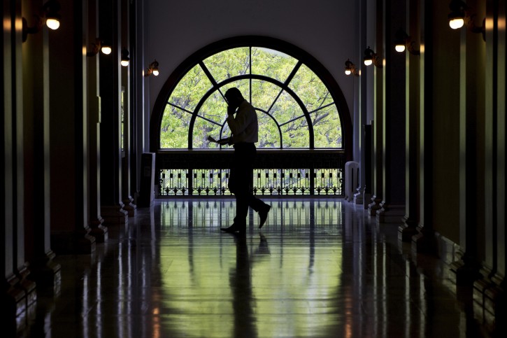 A Capitol Hill staffer looks down at papers while on a cell phone while walking inside the Russell Senate Office Building on Capitol Hill in Washington, Thursday, April 30, 2015. (AP Photo/Jacquelyn Martin)