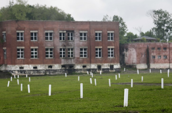 In this May 23, 2018 photo, each white marker denotes a mass grave of about 150 people on Hart Island in New York. Officials let reporters get a rare look at Hart Island, the place that has served as New York Cityâs potterâs field for 150 years. (AP Photo/Seth Wenig)