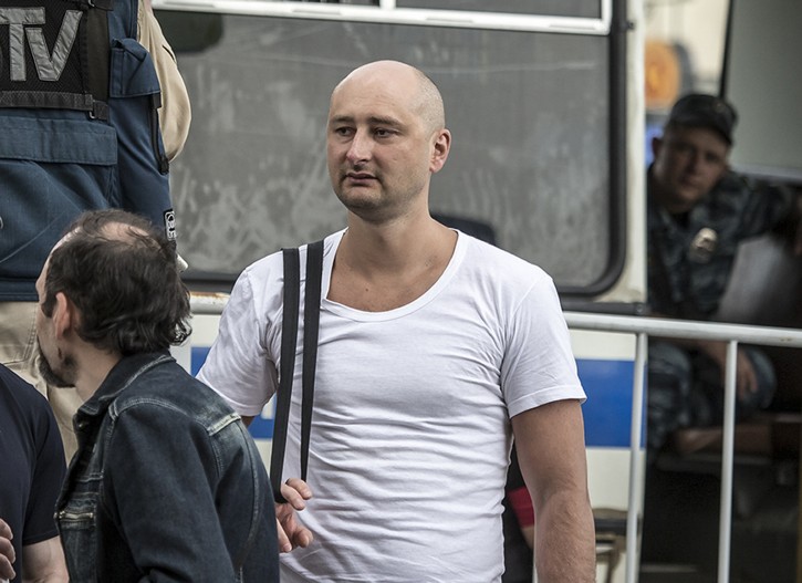 In this photo taken on Friday, May 31, 2013, Arkady Babchenko, 41, who had been scathingly critical of the Kremlin in recent years, stands at a police bus during an opposition rally in Moscow, Russia. (AP Photo/Alexander Baroshin)