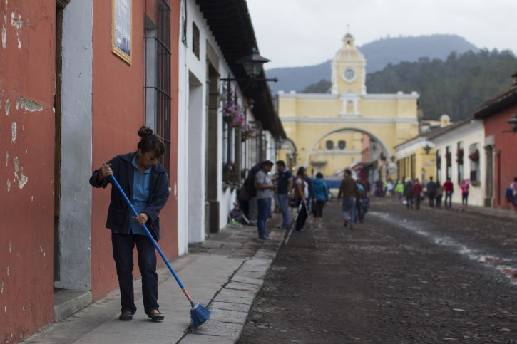 A woman sweeps volcanic ash brought by the Volcan del Fuego, from the sidewalk in Antigua Guatemala, Sunday, June 3, 2018. Volcan del Fuego is one of the most active volcanoes in Central America. (AP Photo/Luis Soto)
