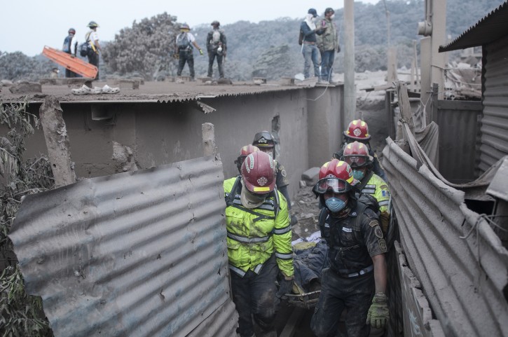 Firefighters remove a body recovered near the Volcan de Fuego, or "Volcano of Fire," in Escuintla, Guatemala, Monday, June 4, 2018. Rescuers have found the bodies of several more victims of an eruption at Guatemala's Volcano of Fire, and emergency workers have pulled some people still alive from ash drifts and mud flows. (AP Photo/Oliver de Ros)