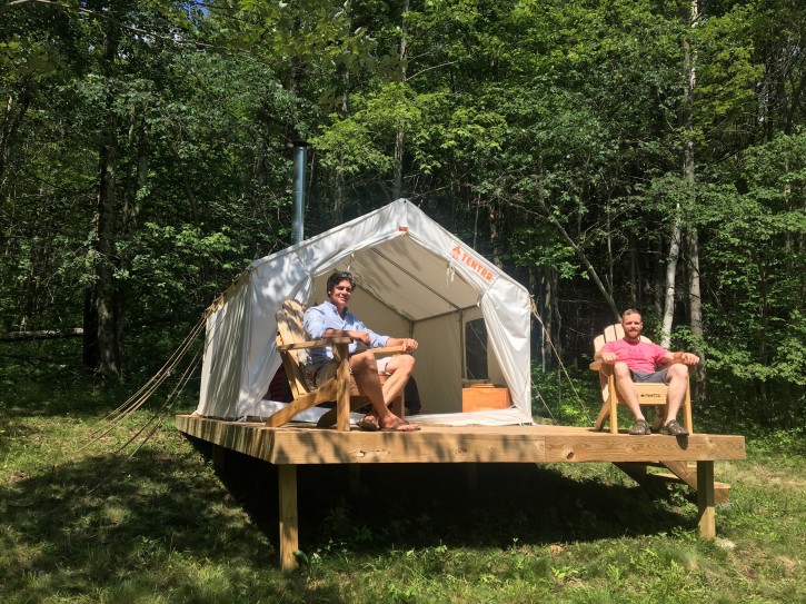In this Friday, June 29, 2018, photo, Michael D'Agostino, left, sits with David Derstine at his Tentrr campsite on a 200-acre organic farm in Berlin, N.Y. D'Agostino, CEO of Tentrr, says it's like Airbnb or Uber for the great outdoors, providing a platform for landowners to earn some cash by sharing secluded and scenic sites for camping. (AP Photo/Mary Esch)