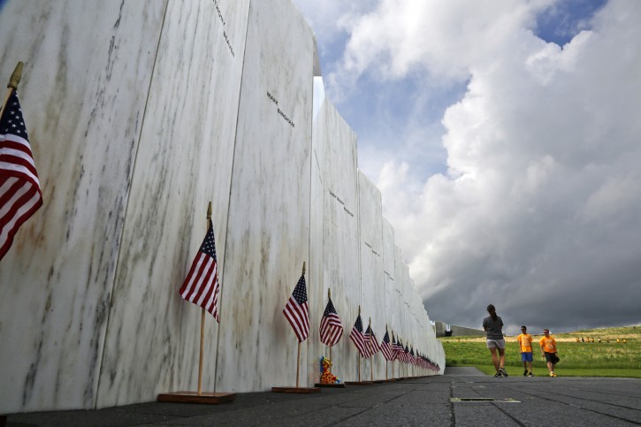 FILE - In this May 31, 2018, file photo, visitors to the Flight 93 National Memorial pause at the Wall of Names honoring 40 passengers and crew members of United Flight 93 killed when the hijacked jet crashed at the site during the 9/11 terrorist attacks, near Shanksville, Pa. Four shipping containers holding the remaining wreckage of United Flight 93 were buried near the Wall of Names in a private ceremony on June 21, 2018, the Flight 93 National Memorial said Monday, July 9, 2018. (AP Photo/Gene J. Puskar, File)