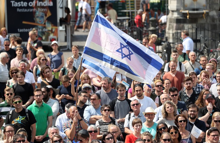 People wave Israeli flags during the kippah day at the market square in front of the historic town hall in Bonn, Germany, 19 July 2018. After the attack and the subsequent police violence against a Jewish professor, the city of Bonn wants to set a sign against anti-Semitism with the Kippah Day.  EPA