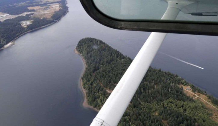 Smoke rises from the site on Ketron Island in Washington state where an Horizon Air turboprop plane crashed Friday after it was stolen from Sea-Tac International Airport as seen from the air, Saturday, Aug. 11, 2018, near Steilacoom, Wash.
