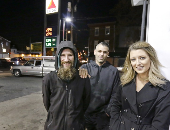 FILE - In this Nov. 17, 2017, file photo, Johnny Bobbitt Jr., left, Kate McClure, right, and McClure's boyfriend Mark D'Amico pose at a Citgo station in Philadelphia. Bobbitt, a homeless man whose selfless act of using his last $20 to fill the gas tank of a stranded motorist in Philadelphia drew worldwide attention, filed suit against D'Amico and McClure, the couple who led a $400,000 GoFundMe fundraising campaign to help him, contending the couple mismanaged donations and committed fraud by taking contributed money for themselves. A hearing is scheduled Thursday, Aug. 30, 2018. (Elizabeth Robertson/The Philadelphia Inquirer via AP, File)