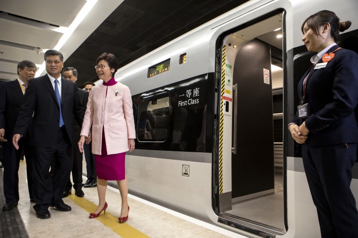 Ma Xingrui, governor of Guangdong Province, front row left, and Carrie Lam, Hong Kong's chief executive, front row second left, stand next to a Guangzhou-Shenzhen-Hong Kong Express Rail Link (XRL) Vibrant Express train bound for Guangzhou Nan Station on a platform in the Mainland Port Area at West Kowloon Station, which houses the terminal for the XRL, developed by MTR Corp., in Hong Kong, China, on Saturday, Sept. 22, 2018. AP