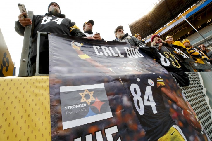 Fans stand above a banner with a Pittsburgh Steelers logo that has one of the hypocycloids changed to a Star of David at at Heinz Field for an NFL football game between the Pittsburgh Steelers and the Cleveland Browns, Sunday, Oct. 28, 2018, in Pittsburgh. The Steelers added the logo in respect for the victims of a deadly shooting in a Pittsburgh synagogue on Saturday. (AP Photo/Gene J. Puskar)