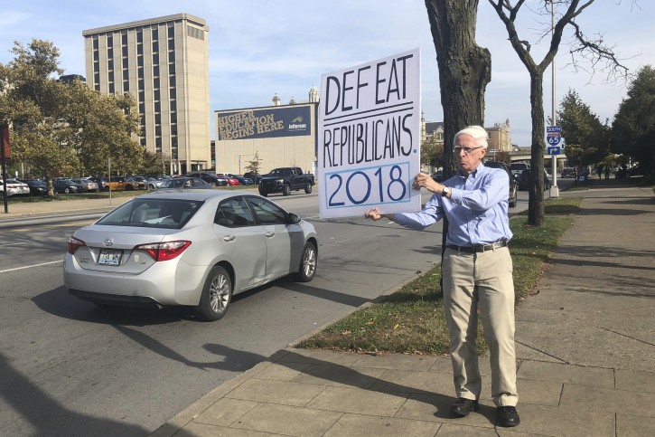 In this Oct. 30, 2018 photo, Michael Gregoire holds a hand-painted sign which reads, âDefeat Republicans 2018,â along a street in Louisville, Ky. âThe survival of the country is going to depend on this election,â he said. (AP Photo/Claire Galofaro)