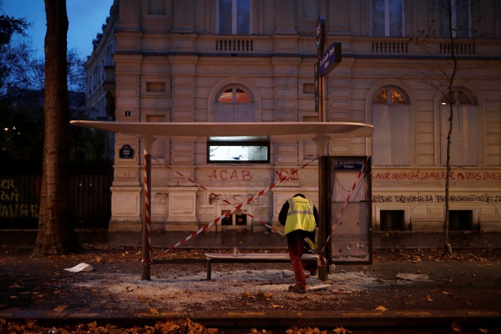An employee inspects a vandalized bus stop the morning after clashes with protesters wearing yellow vests, a symbol of a French drivers' protest against higher diesel fuel taxes, in Paris, France, December 2, 2018. REUTERS/Benoit Tessier