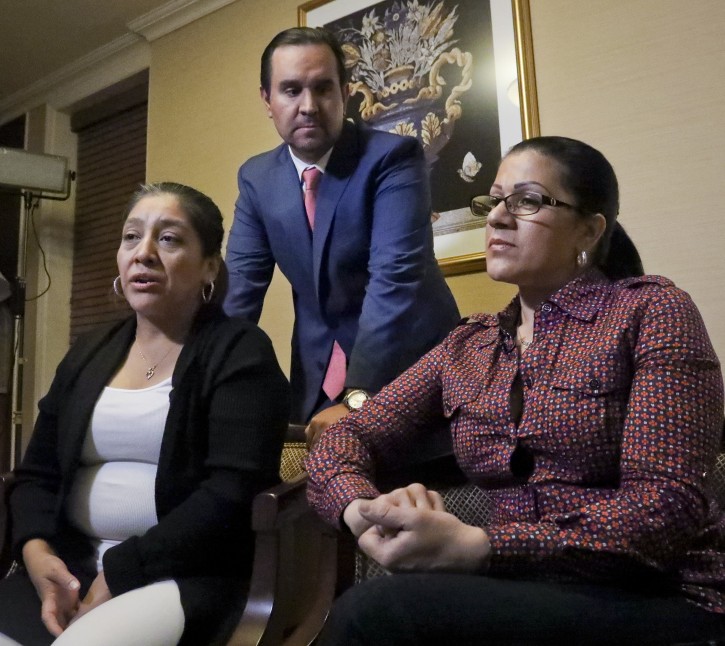 Attorney Anibal Romero, center, joins his clients Victorina Morales, left, and Sandra Diaz, right, during an interview, Friday Dec. 7, 2018, in New York. Morales and Diaz, who recalled their experience working at President Donald Trump's golf resort in Bedminster, N.J., say they used false legal documents to get hired and supervisors knew it. (AP Photo/Bebeto Matthews)