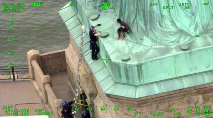 FILE - In this July 4, 2018 file photo, of a frame from video provided by the New York City Police Department, members of the NYPD Emergency Service Unit work to safely remove Therese Okoumou, who climbed onto the Statue of Liberty to protest the border separation of children. (NYPD via AP, FIle)