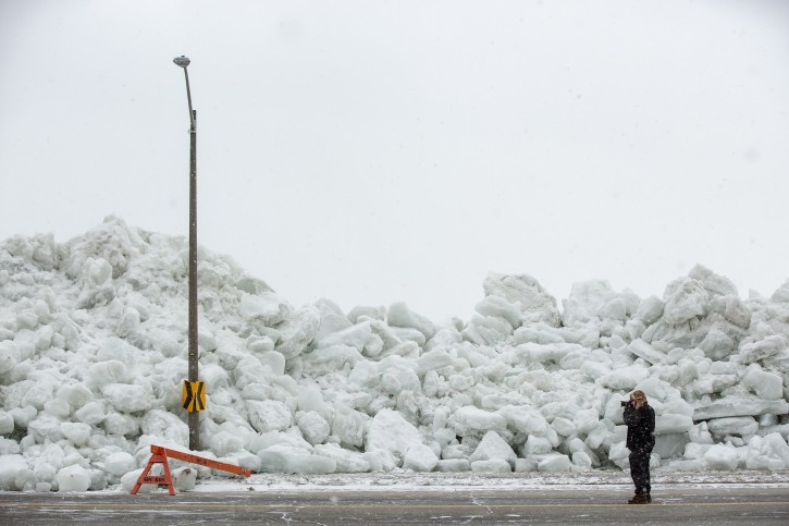 A man photographs a massive build up of ice that was pushed onto the shore of Mather Park in Fort Erie, Ont., Monday, February 25, 2019. A windstorm Sunday broke an ice boom in Lake Erie and allowed the ice, which was floating on the water at the mouth of the Niagara River, to shove over the retaining wall and onto the shore and the roadway above. (Tara Walton/The Canadian Press via AP)
