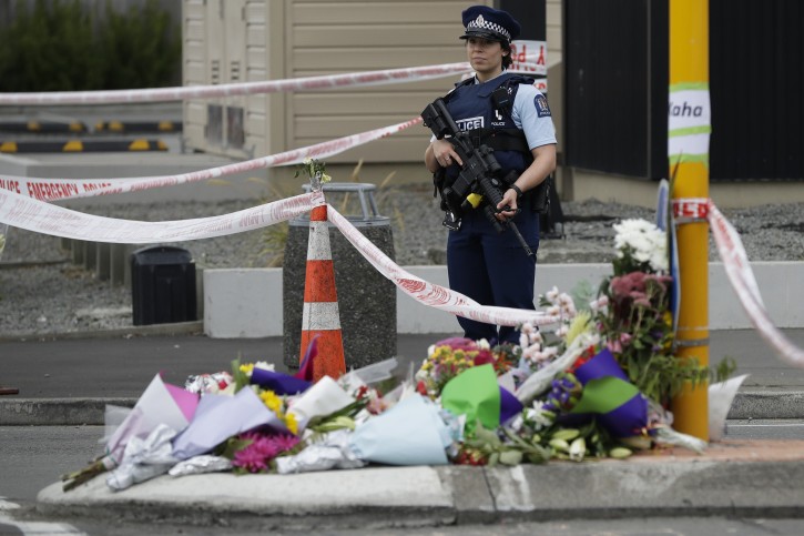Police stand by a collection of flowers near the Linwood Mosque in Christchurch, New Zealand, Saturday, March 16, 2019, where one of the two mass shootings occurred. (AP Photo/Mark Baker)