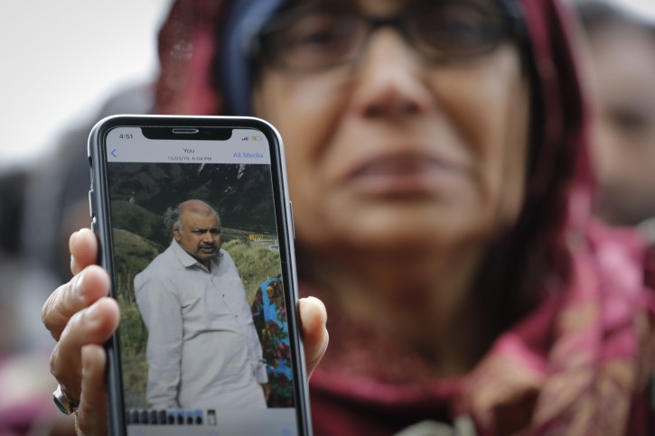 Akhtar Khokhur, 58, shows a picture of her missing husband Mehaboobbhai Khokhar during an interview outside an information center for families, Saturday, March 16, 2019, in Christchurch, New Zealand. The white supremacist gunman appeared in court Saturday charged with murder in the mosque assaults that killed at least 50 people and led to the prime minister to call for a tightening of national gun laws. (AP Photo/Vincent Thian)