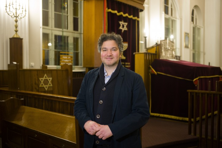 This Wednesday, March 20, 2019 photo Jonathan Marcus a German member of 'Fraenkelufer' synagogue poses for a photo inside the prayer room of the so-called youth-synagogue, the remaining building of the 'Fraenkelufer' synagogue, in Berlin. The synagogue was able to receive about 2000 prayers before it was destroyed by the Nazis. In the German capital, efforts are underway to rebuild the synagogue.  (AP Photo/Markus Schreiber)