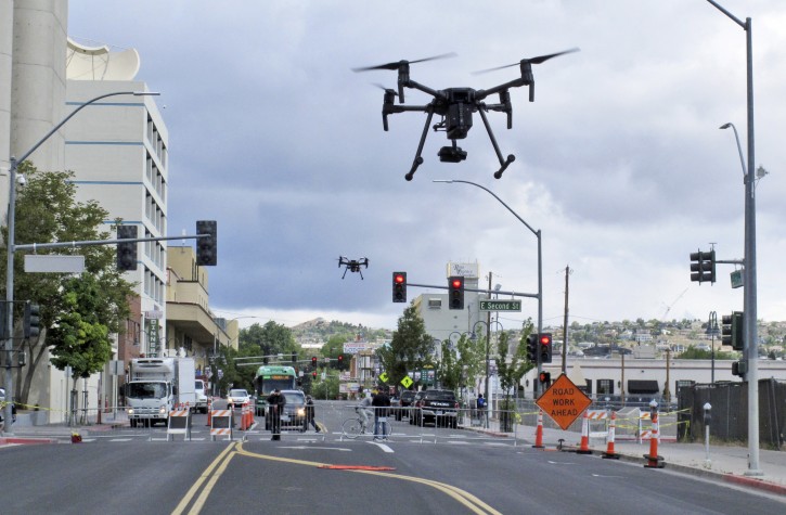 Two drones fly above Lake Street in downtown Reno on Tuesday, May 21, 2019 as part of a NASA simulation to test emerging technology that someday will be used to manage travel of hundreds of thousands of commercial, unmanned aerial vehicles (UAVs) delivering packages. It marked the first time such tests have been conducted in an urban setting. (AP Photo/Scott Sonner)
