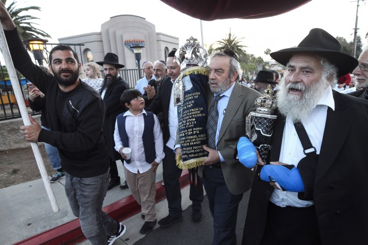 Howard Kaye, center, husband of Lori Gilbert-Kaye, carries the new torah as Rabbi Yisarel Goldstein, right, and other members of the Chabad of Poway synagogue celebrate the completion of new torah dedicated to Lori Gilbert-Kaye, who was killed when a gunman attacked last April, at Chabad of Poway on Wednesday, May 22, 2019 in Poway, California. AP