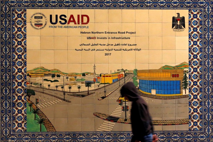 FILE PHOTO: A Palestinian walks past a ceramic sign of a U.S. Agency for International Development (USAID) project in Hebron in the Israeli-occupied West Bank January 31, 2019. REUTERS/Mussa Qawasma/File Photo