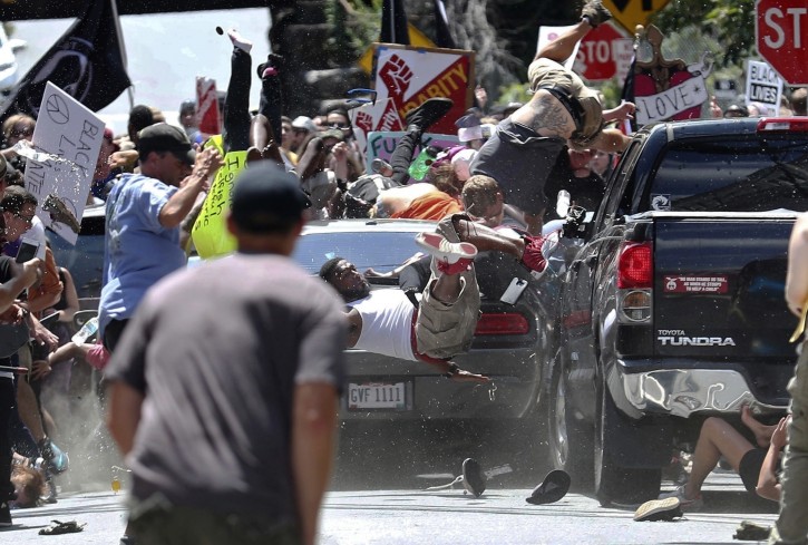 FILE - In this Aug. 12, 2017, file photo, people fly into the air as a vehicle is driven into a group of protesters demonstrating against a white nationalist rally in Charlottesville, Va. AP